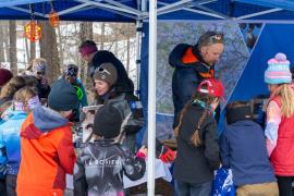 Trois gardes-moniteurs du Parc national de la Vanoise, sous une tonnelle, animant un stand avec des enfants.
